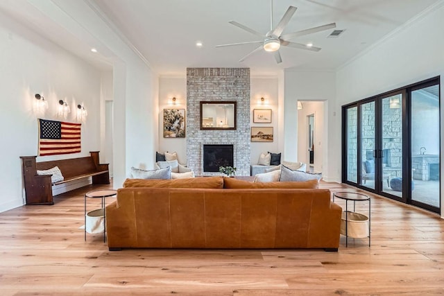 living room with ceiling fan, visible vents, light wood finished floors, and ornamental molding