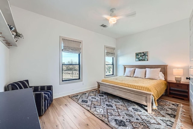 bedroom featuring a ceiling fan, wood finished floors, visible vents, and baseboards