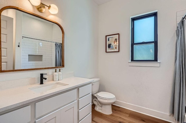 bathroom featuring baseboards, toilet, a shower with shower curtain, wood finished floors, and vanity