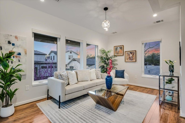 living area with a wealth of natural light, visible vents, baseboards, and wood finished floors