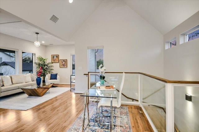 office space with a healthy amount of sunlight, wood finished floors, visible vents, and high vaulted ceiling