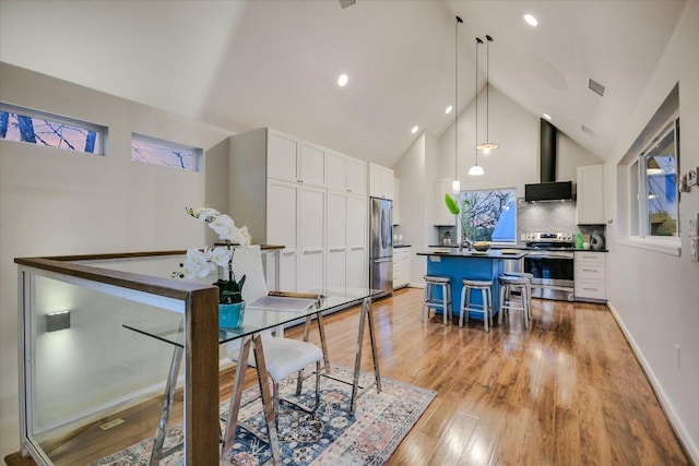 dining room featuring visible vents, baseboards, high vaulted ceiling, and light wood-style flooring