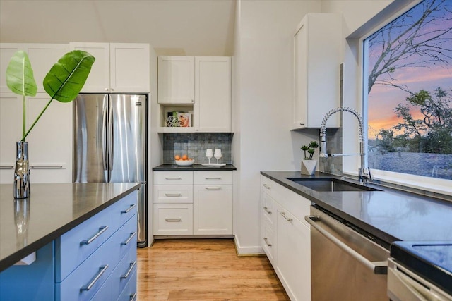 kitchen with white cabinets, light wood finished floors, appliances with stainless steel finishes, and a sink