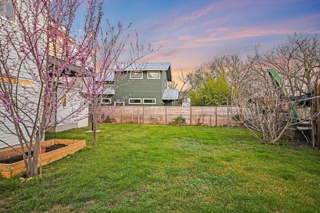 yard at dusk featuring a garden and fence private yard