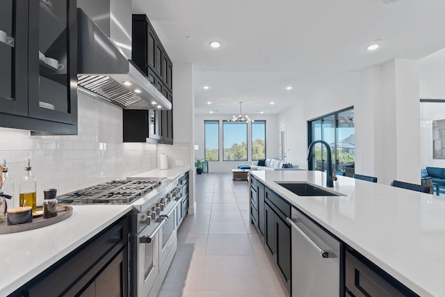 kitchen with a sink, stainless steel appliances, open floor plan, and wall chimney exhaust hood