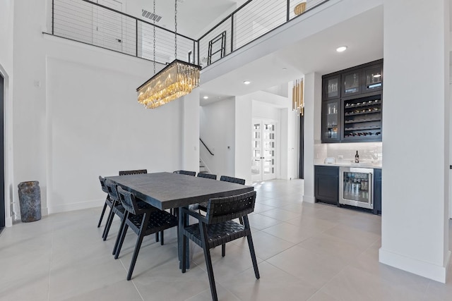 dining room with beverage cooler, a high ceiling, indoor wet bar, baseboards, and stairs