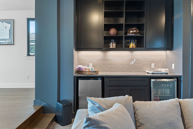 bar with beverage cooler, tasteful backsplash, indoor bar, and stainless steel refrigerator