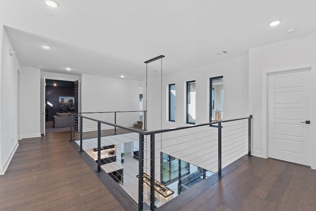 hallway featuring dark wood finished floors, recessed lighting, and an upstairs landing