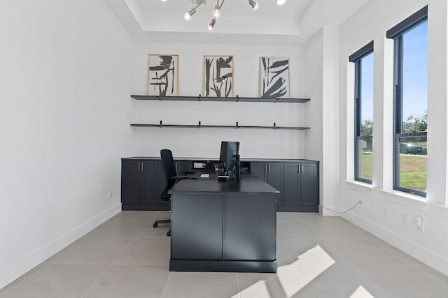 office area featuring a raised ceiling, a notable chandelier, light tile patterned floors, and baseboards