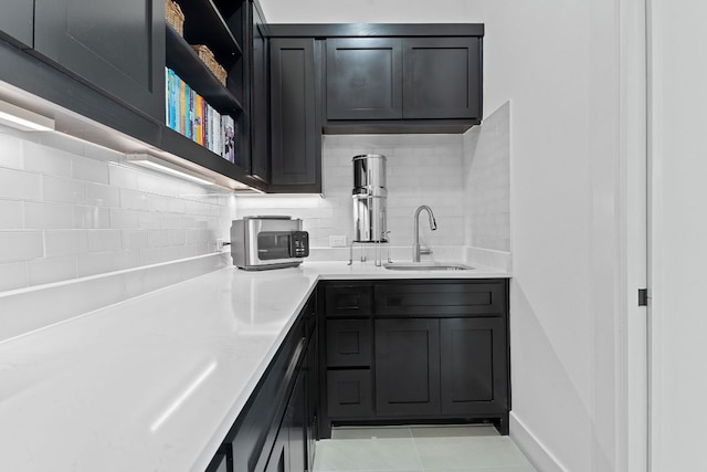 kitchen featuring a sink, open shelves, backsplash, light tile patterned flooring, and light countertops