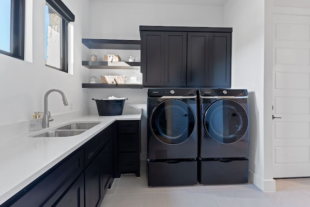 clothes washing area featuring washer and clothes dryer, light tile patterned floors, cabinet space, and a sink