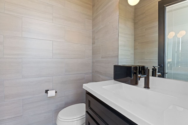 bathroom with vanity, tile walls, and toilet