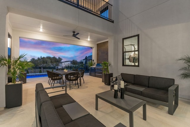 patio terrace at dusk featuring ceiling fan, fence, an outdoor hangout area, outdoor dining area, and a balcony