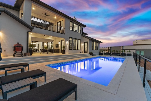 pool at dusk with an outdoor pool, outdoor dining area, a patio, and ceiling fan