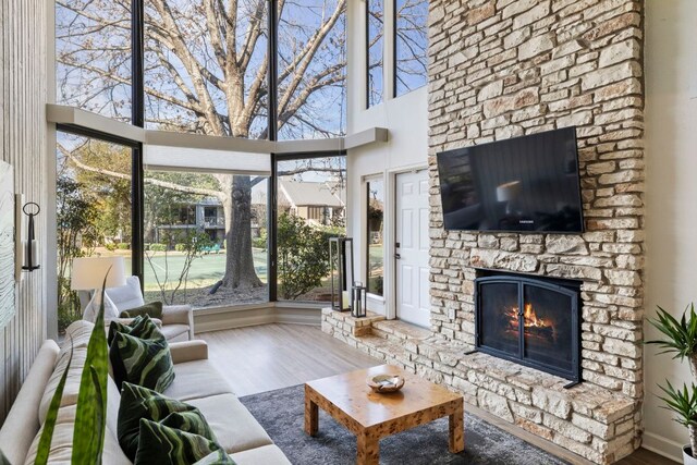 111 World Of Tennis Sq, Lakeway, TX 78738 - living room featuring a towering ceiling, a stone fireplace, wood finished floors, and healthy amount of natural light
