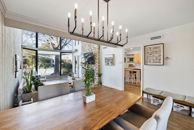 dining room with visible vents, wood finished floors, a notable chandelier, and ornamental molding