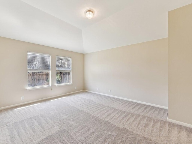 carpeted spare room with lofted ceiling and baseboards