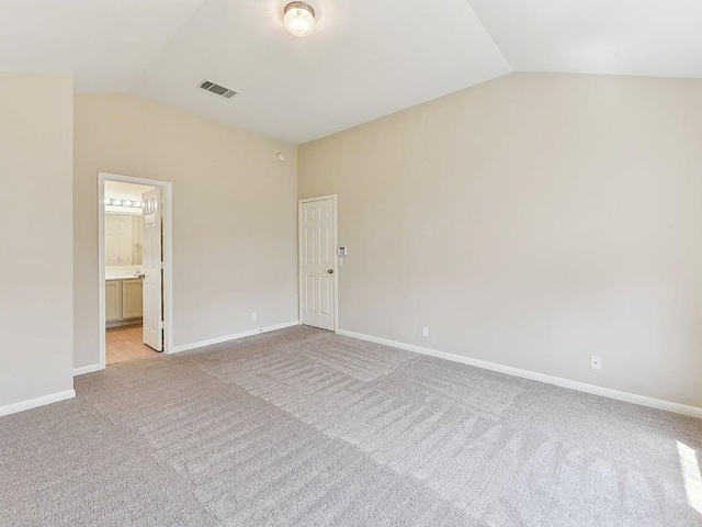 spare room featuring visible vents, lofted ceiling, light colored carpet, and baseboards