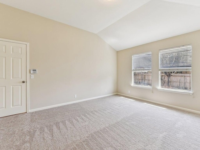 carpeted empty room with baseboards and lofted ceiling