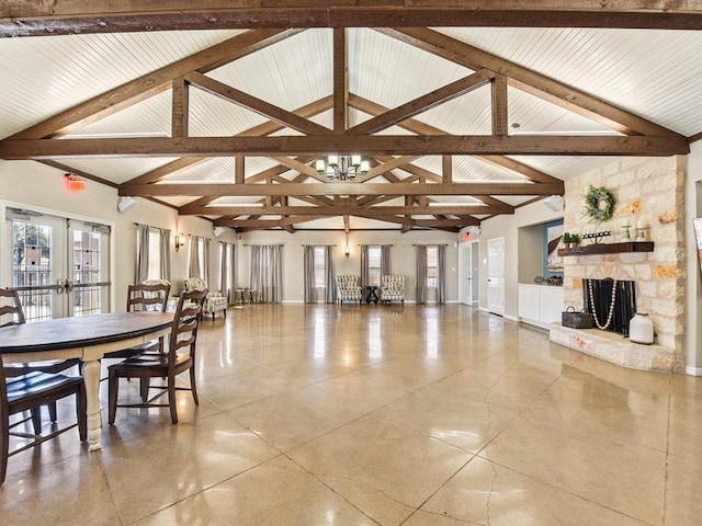 interior space featuring a fireplace, lofted ceiling with beams, french doors, and an inviting chandelier