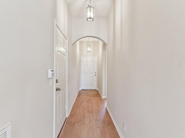 entryway featuring light wood-style flooring, baseboards, and arched walkways