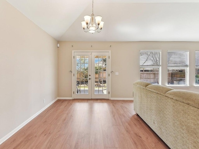 unfurnished living room with an inviting chandelier, wood finished floors, a healthy amount of sunlight, and french doors