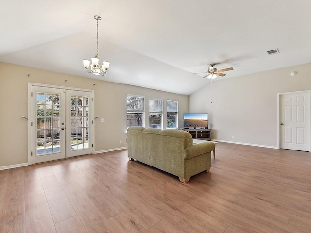 living room featuring vaulted ceiling, ceiling fan with notable chandelier, visible vents, and a healthy amount of sunlight