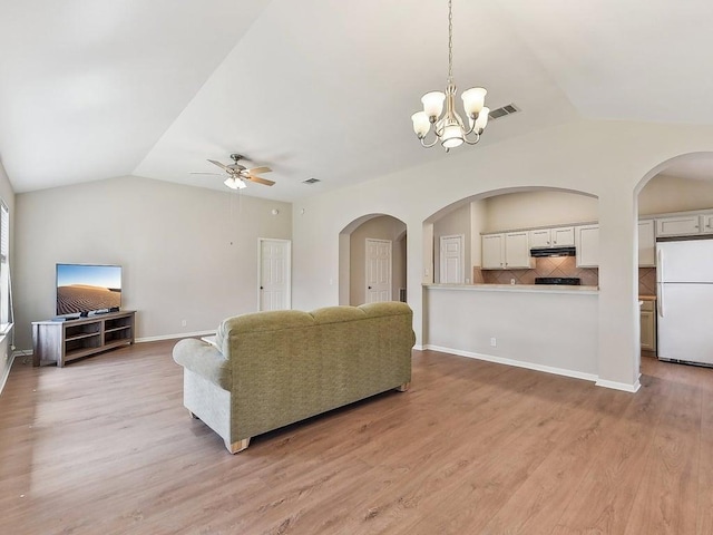 living area with visible vents, ceiling fan with notable chandelier, light wood finished floors, baseboards, and vaulted ceiling