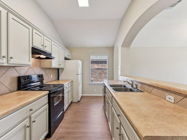 kitchen featuring black / electric stove, arched walkways, a sink, vaulted ceiling, and under cabinet range hood