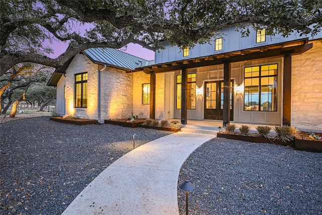 exterior space featuring metal roof, stone siding, covered porch, and a standing seam roof