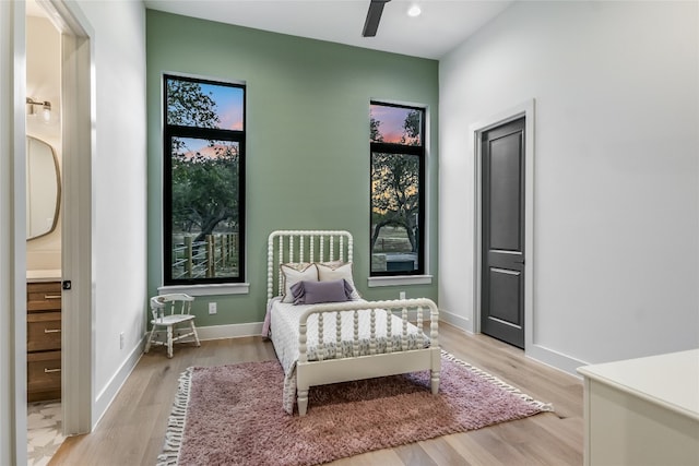 bedroom featuring baseboards, light wood-style flooring, and a ceiling fan