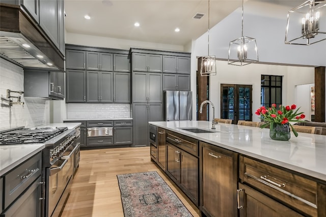 kitchen featuring visible vents, premium range hood, appliances with stainless steel finishes, light wood-style floors, and a sink