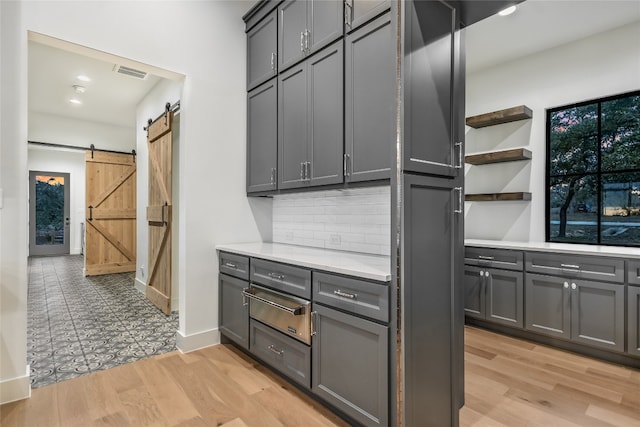 kitchen with visible vents, gray cabinets, light countertops, and a barn door