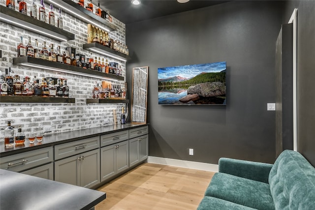 bar with recessed lighting, light wood-type flooring, bar area, and baseboards