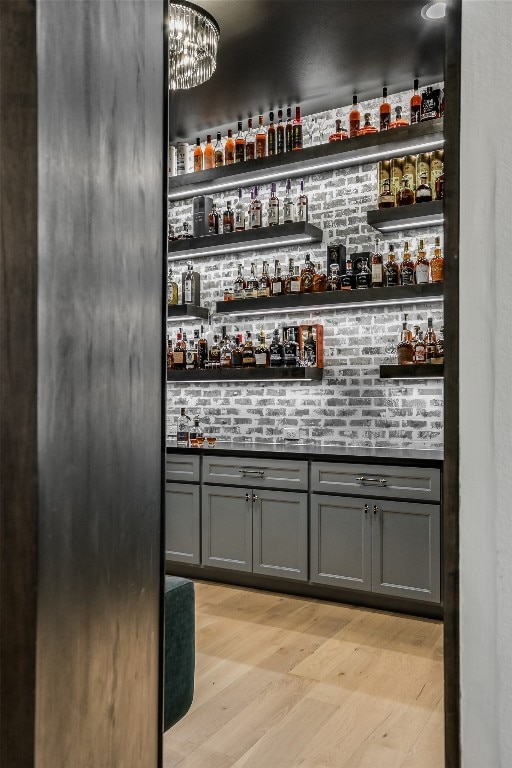 bar featuring a notable chandelier, light wood-style floors, and a dry bar