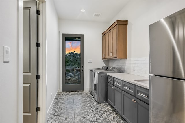 laundry area featuring visible vents, cabinet space, separate washer and dryer, light tile patterned flooring, and baseboards