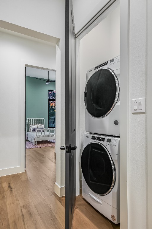 laundry area with wood finished floors, laundry area, and stacked washing maching and dryer