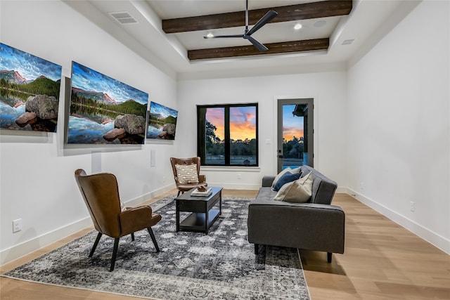 living area featuring beam ceiling, visible vents, light wood-type flooring, and a ceiling fan