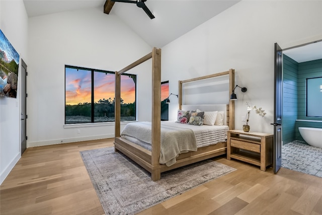 bedroom with beam ceiling, wood finished floors, baseboards, and high vaulted ceiling