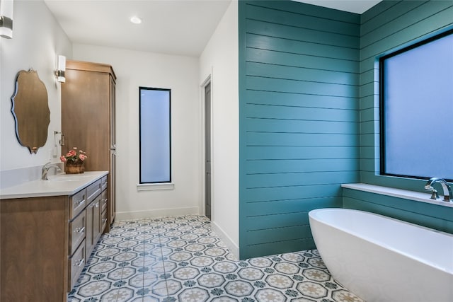 bathroom with vanity, a freestanding tub, baseboards, and wood walls