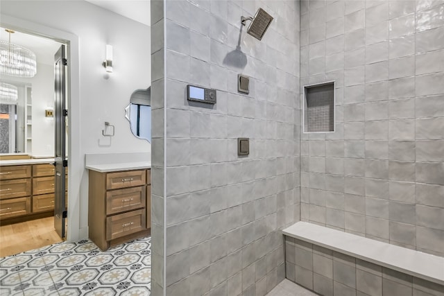 bathroom with a notable chandelier, vanity, and a tile shower