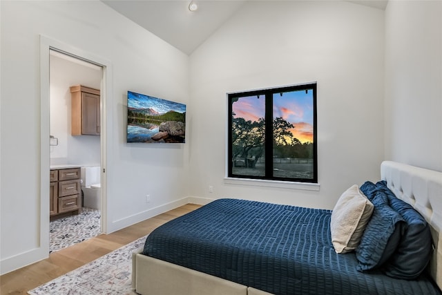 bedroom with ensuite bath, vaulted ceiling, light wood-style floors, and baseboards