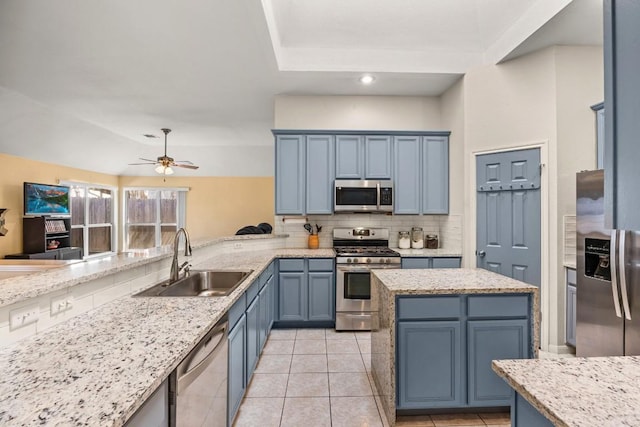 kitchen featuring a sink, blue cabinetry, tasteful backsplash, appliances with stainless steel finishes, and a peninsula