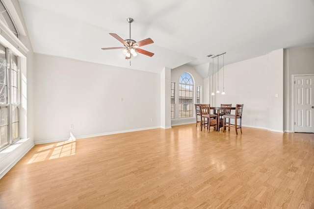 empty room with baseboards, lofted ceiling, a ceiling fan, and light wood finished floors