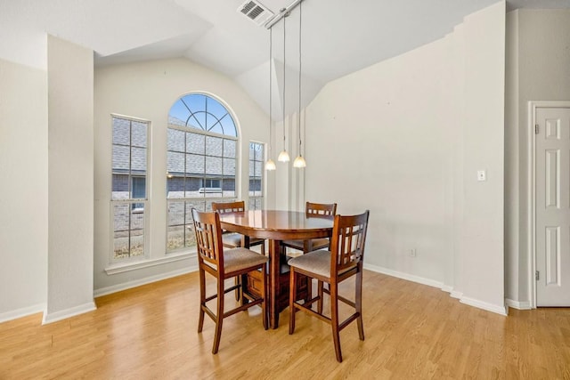 dining space with light wood finished floors, visible vents, baseboards, and vaulted ceiling