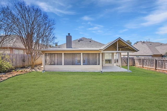 rear view of property with a lawn, a chimney, a fenced backyard, and a sunroom