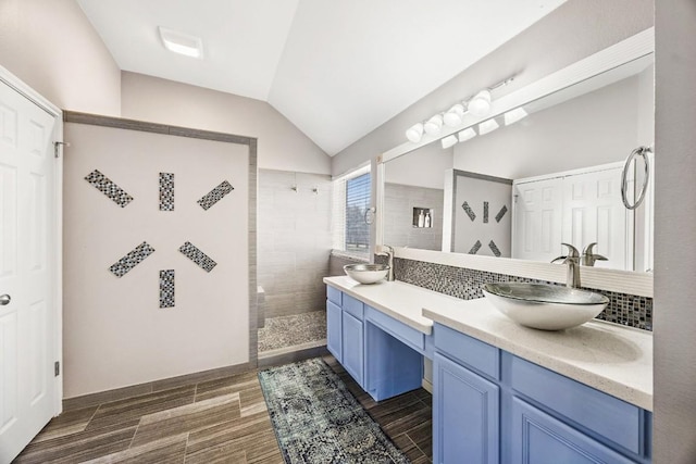 bathroom featuring vaulted ceiling, wood finish floors, walk in shower, and a sink