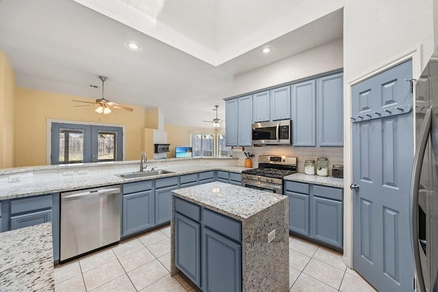 kitchen with ceiling fan, light tile patterned floors, decorative backsplash, appliances with stainless steel finishes, and a sink