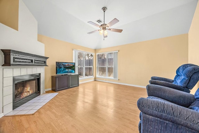 living area featuring lofted ceiling, a ceiling fan, wood finished floors, a fireplace, and baseboards