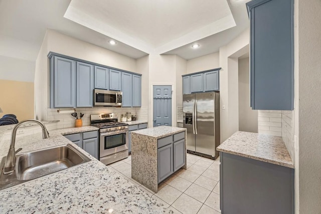 kitchen with light stone counters, tasteful backsplash, appliances with stainless steel finishes, and a sink